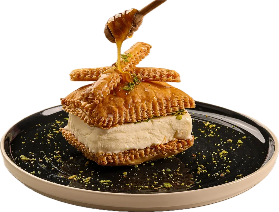 Arabic ice cream pressed between two discs of pastry, with syrup being poured over it.